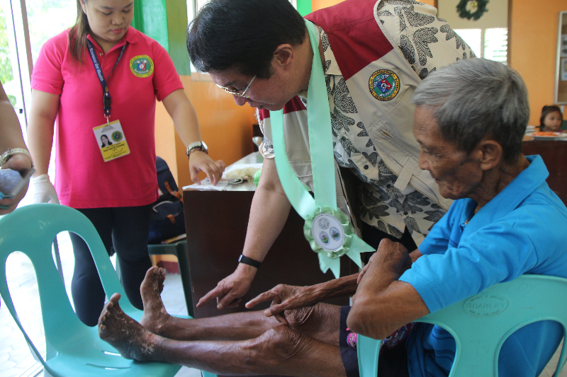 DOH-MIMAROPA Regional Director Eduardo C. Janairo inspects the affected part of a patient with skin disease during a visit to the on-site rapid health assessment held in Barangay Tabique in Boac, Marinduque on October 3, 2017